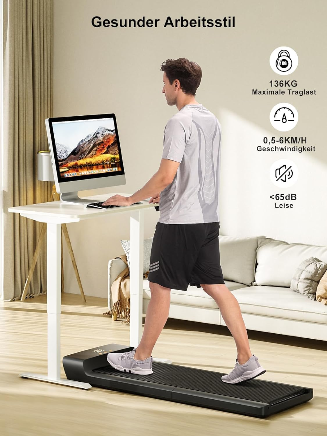 Ein Mann nutzt einen Stehtisch mit Computer, während er auf dem Kingsmith WalkingPad A1 Pro, einem klappbaren Laufband (6 km/h, 136 kg), im Wohnzimmer läuft; die Produktspezifikationen werden auf Deutsch angezeigt.