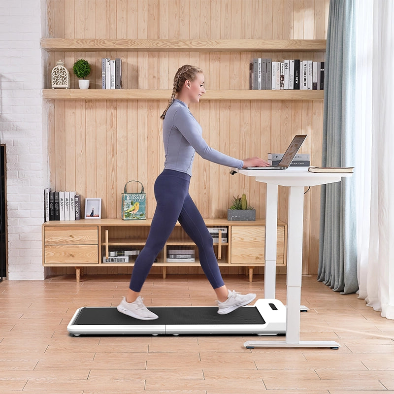 Eine Frau benutzt das Kingsmith WalkingPad C2 Klappbares Laufband, während sie an einem Stehpult in einem hellen, modernen Wohnzimmer an ihrem Laptop arbeitet.