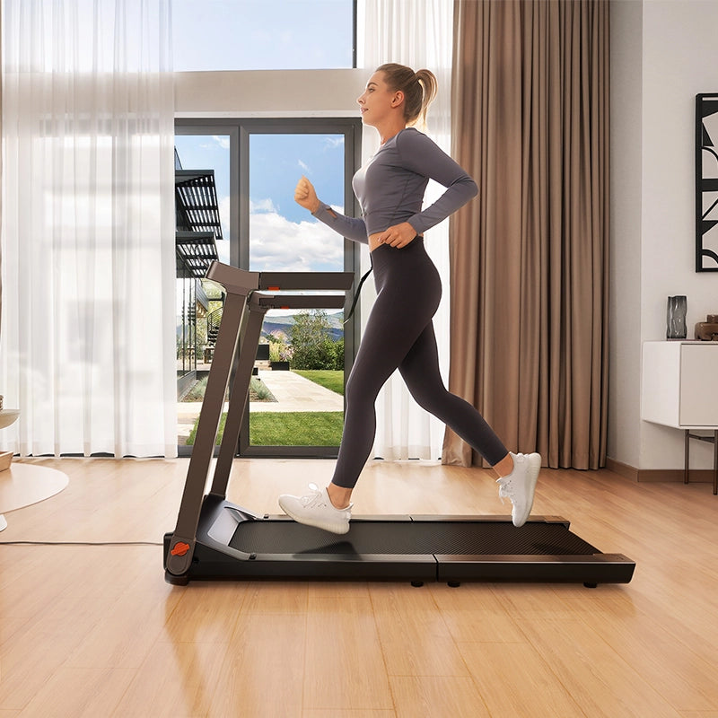 Eine Frau joggt auf dem Kingsmith WalkingPad G1 Klappbares Laufband mit Handläufen in einem hellen, modernen Wohnzimmer mit großen Fenstern und Holzboden und nutzt die integrierte App, um ihr Training zu verfolgen.