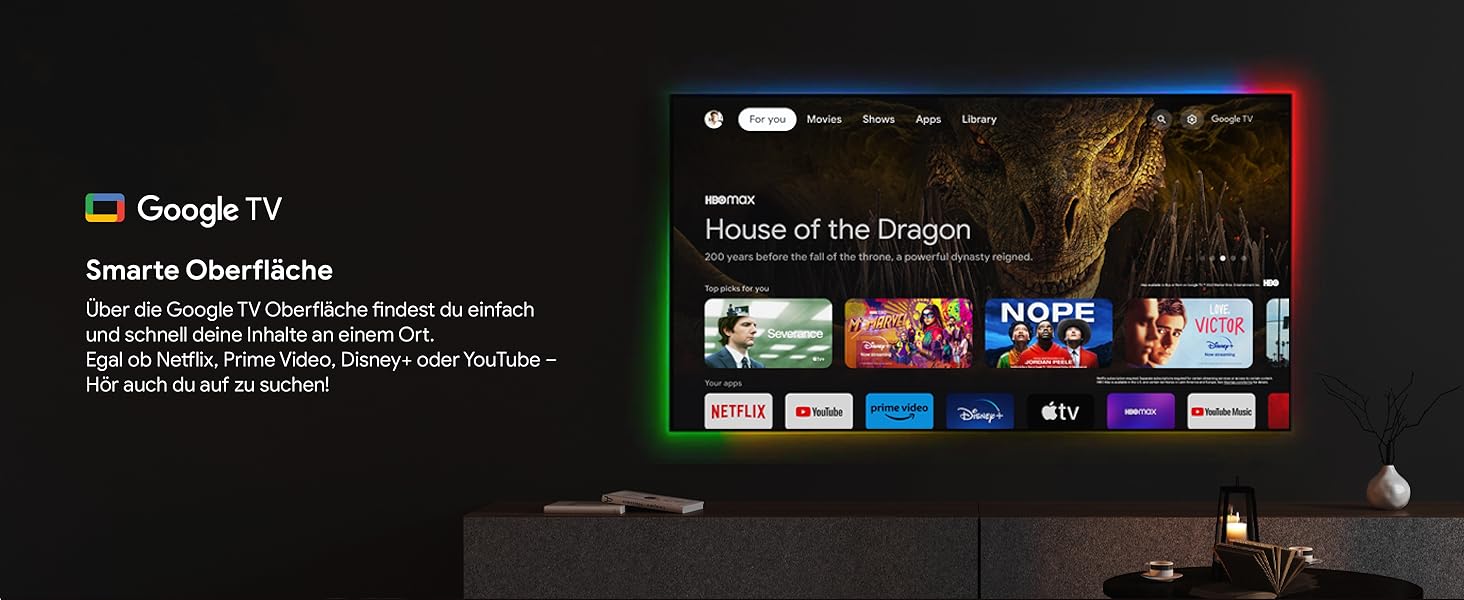 Ein Wohnzimmer mit einem an der Wand montierten Fernseher, auf dem die Google TV-Oberfläche mit der Sendung House of the Dragon und verschiedenen Streaming-App-Symbolen darunter angezeigt wird.