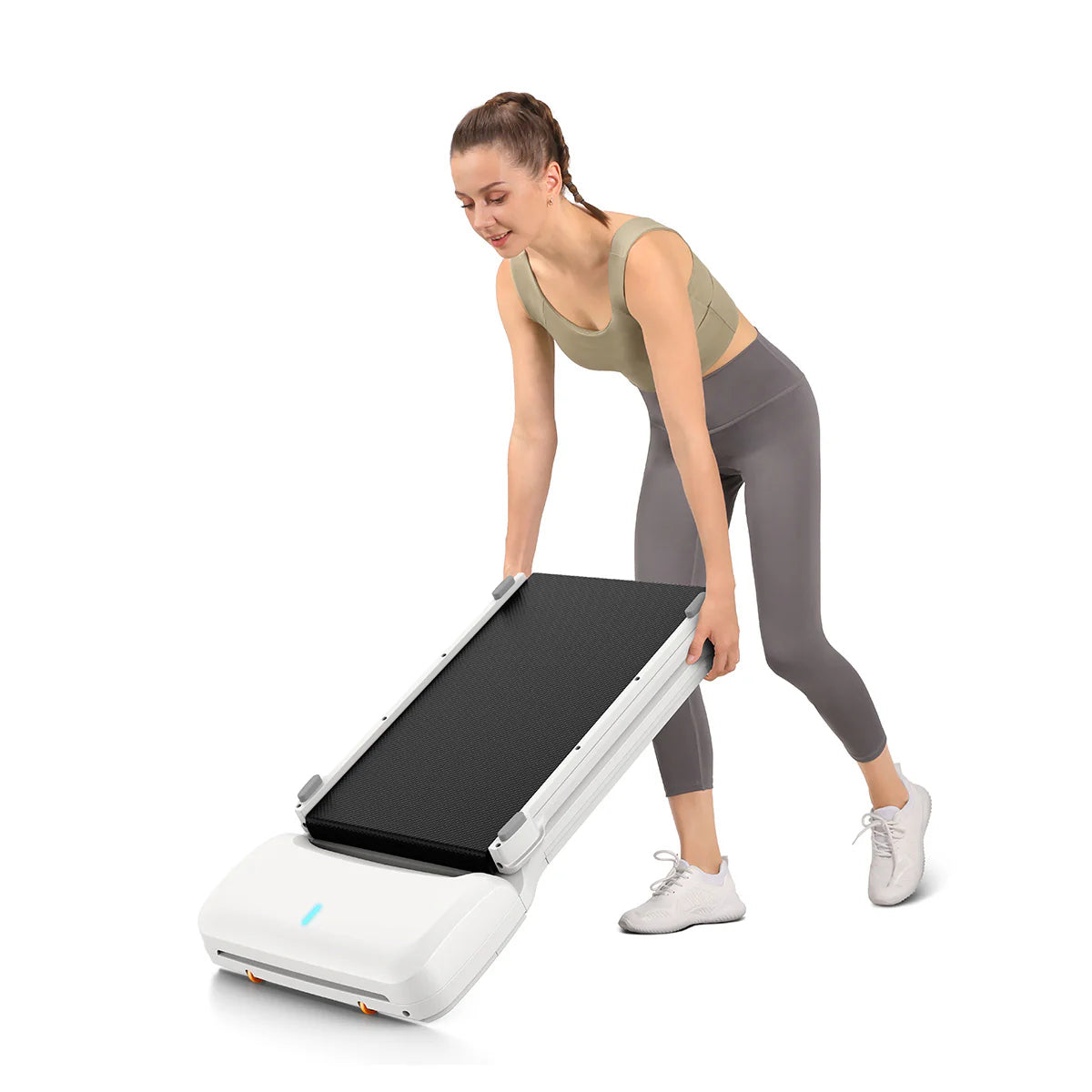 Eine Frau in Sportkleidung hebt und faltet das Kingsmith WalkingPad C1 Mini Klappbares Laufband für Schreibtisch vor weißem Hintergrund-ideal zur platzsparenden Aufbewahrung im Homeoffice.