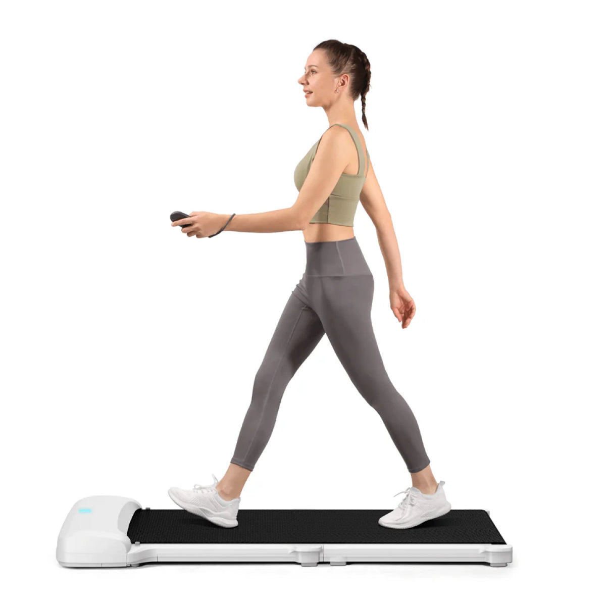 Eine Frau in Sportkleidung benutzt das Kingsmith WalkingPad C1 Mini klappbares Laufband für Schreibtisch und hält eine Fernbedienung in der Hand - ideal, um aktiv zu bleiben, während man von zu Hause aus arbeitet, isoliert auf einem weißen Hintergrund.