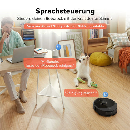 Ein Mann arbeitet am Schreibtisch, während sein Hund in der Nähe sitzt und der Roborock Q8 Max Special Edition den Boden reinigt; Symbole und Text zeigen die Kompatibilität mit der Sprachsteuerung.