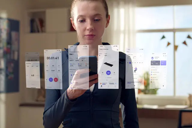 Eine Frau steht in einem Innenraum und benutzt ein Smartphone. Vor ihr werden mehrere virtuelle App-Schnittstellen projiziert, was auf ein Augmented-Reality- oder futuristisches Technologiekonzept hindeutet.