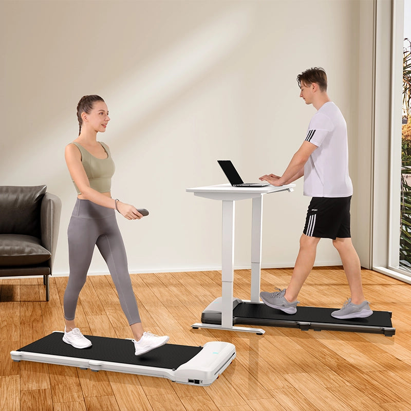 Eine Frau benutzt ein Kingsmith WalkingPad C1 Klappbares Laufband mit Fernbedienung, während ein Mann an seinem Stehpult in einem hellen Wohnzimmer arbeitet - ideal für Homeoffice Fitness.