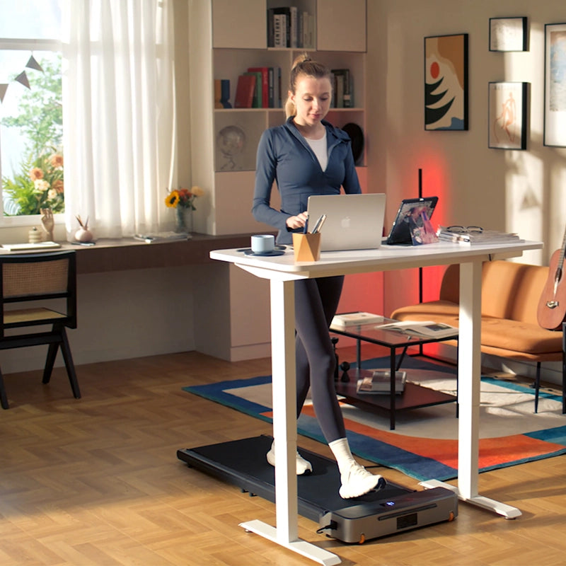 Eine Frau arbeitet an einem Stehpult, während sie auf dem Kingsmith WalkingPad Z1 Klappbares Laufband für Schreibtisch in einem hellen, modernen Heimbüro läuft.