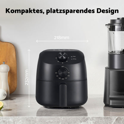 Die schwarze aeco Cube 2.0 Airfryer 2 Liter mit intuitiven Drehreglern passt perfekt auf die Küchenarbeitsplatte; ihr kompaktes Design misst 218 mm in der Breite und 232 mm in der Höhe. Küchenutensilien und ein Mixer in der Nähe unterstreichen, wie nahtlos sich dieses platzsparende Gerät in jede moderne Kücheneinrichtung einfügt.