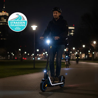 Nachts in einem gut beleuchteten Park fährt ein behelmter Fahrer auf einem Odys ALPHA X5 PRO - E-Scooter. Oben links ist eine runde StVZO-konforme Zulassungsplakette zu sehen. Erleben Sie längere Fahrten mit einer Reichweite von 50 km.
