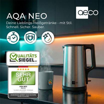 Der aeco AQA NEO Wasserkocher aus Edelstahl steht auf der Küchentheke neben einer dampfenden Tasse und ist mit Qualitäts- und Sicherheitszertifikaten versehen.