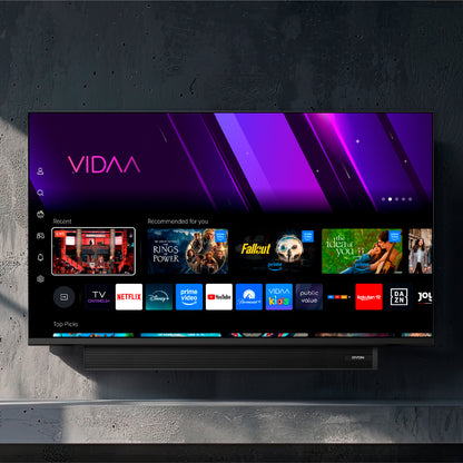 Ein Dyon Movie Smart 32 VX-S (32 Zoll, 80 cm) Flachbildfernseher ist an einer dunklen Wand montiert und zeigt die VIDAA Smart-TV-Oberfläche mit Streaming-Apps und Empfehlungen auf dem Bildschirm.