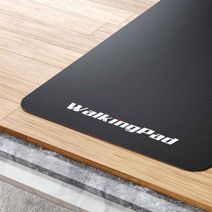 Eine rutschfeste Kingsmith WalkingPad-Laufband-Bodenmatte wird auf einem Holzboden neben einer Stein- oder Marmorfläche ausgelegt.