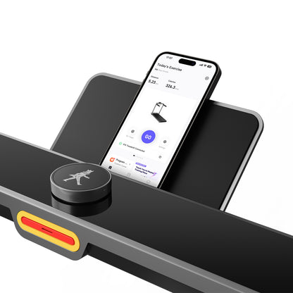 Ein Smartphone mit einer Fitness-App liegt auf dem Kingsmith WalkingPad X214 Klappbares Laufband, das sich durch ein kompaktes, faltbares Design, einen runden Bedienknopf und einen rechteckigen Sensor darunter auszeichnet.