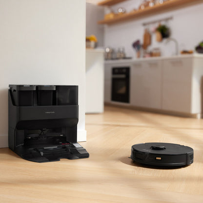 Der Roborock S7 Max Ultra Black Staubsauger arbeitet auf einem Holzboden in der Nähe seiner Lade- und Reinigungsstation in einer modernen, aufgeräumten Küche.