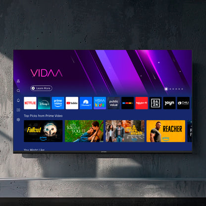 Ein Dyon Smart 43 VX Smart LED-Fernseher wird an der Wand montiert und zeigt die VIDAA Smart TV-Oberfläche mit mehreren Streaming-Apps und Show-Empfehlungen an.